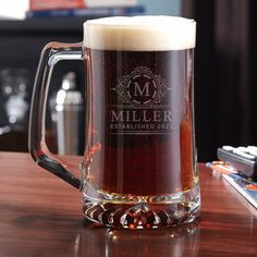 a beer mug sitting on top of a wooden table next to a remote control system