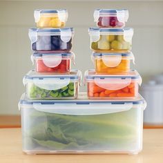 a stack of plastic containers filled with different types of fruits and vegetables on top of a wooden table