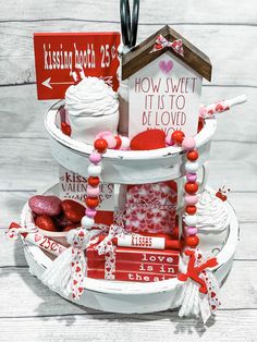 a white cake with red and pink decorations on it's tiered display stand