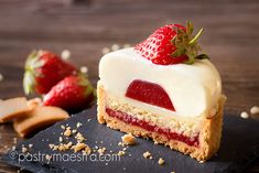 a piece of cake with white frosting and strawberries on top, sitting on a slate board