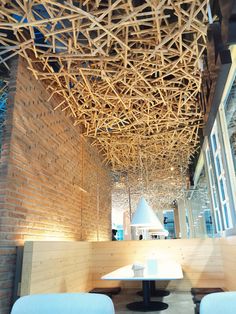 the interior of a restaurant with wooden sticks hanging from the ceiling and chairs around tables