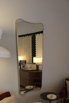 a large mirror hanging on the wall next to a table with two chairs and a lamp