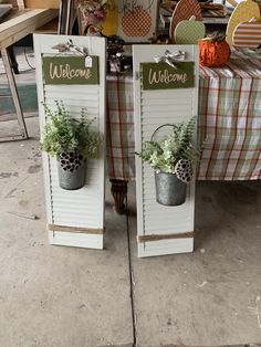 two white shutters with plants and welcome signs on them