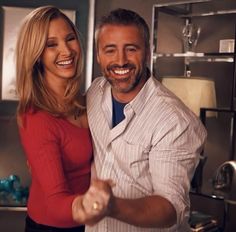 a man and woman are dancing together in the kitchen, smiling at the camera with their arms around each other