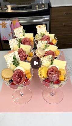 two wine glasses filled with different types of cheese and crackers on top of a table