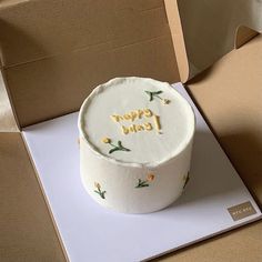 a white cake sitting on top of a table next to an open box with writing