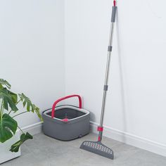 a mop and bucket on the floor next to a potted plant