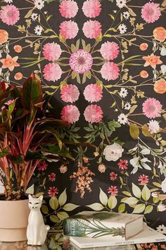 a vase with flowers on top of a table next to a wallpapered wall