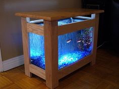 a fish tank that is sitting on top of a wooden table with an aquarium in it