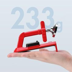 a hand holding a red stapler with the number 23 on it