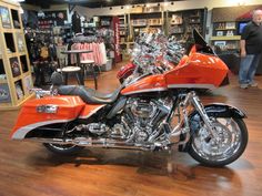 two orange motorcycles are parked in a store