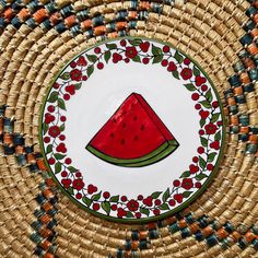 a plate with a watermelon design on it sitting on a woven place mat