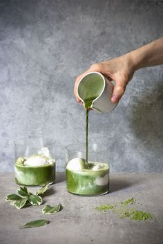 someone pouring green tea into two glasses