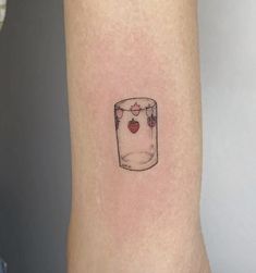 a small strawberry in a glass tattoo on the arm