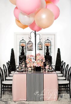 a table topped with lots of pink and white flowers next to a bunch of balloons