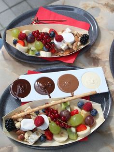 two plates filled with different types of fruit and chocolates on sticks next to each other