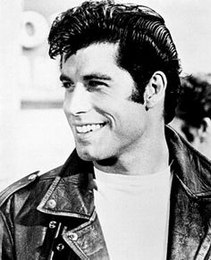 a black and white photo of a man in a leather jacket smiling at the camera