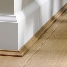 the corner of a room with white trim and wood flooring on it's side