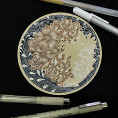 a plate with flowers painted on it next to some markers and pencils in front of it