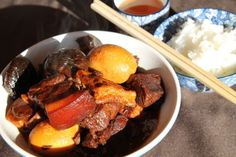 a bowl filled with meat and vegetables next to chopsticks on top of a table