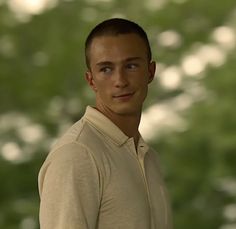 a man standing in front of trees with his eyes wide open and looking at the camera