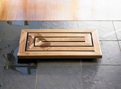 a wooden grate sitting on top of a stone floor next to a tile floor