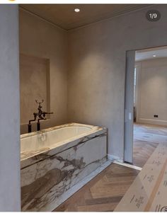 an empty bathroom with marble tub and wooden flooring