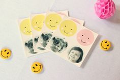 four pictures with smiley faces on them are next to some paper flowers and other decorations