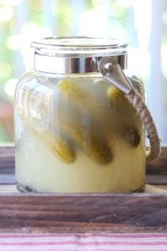 a jar filled with pickles sitting on top of a wooden table