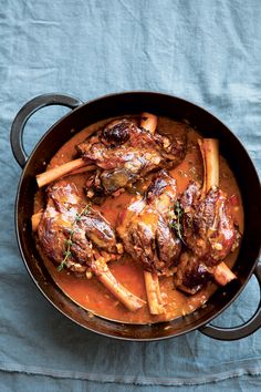 a pot filled with meat and vegetables on top of a blue cloth