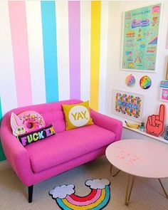 a pink couch sitting next to a white table in a room with colorful striped walls