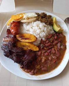 a white plate topped with meat, beans and rice