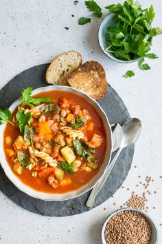 a bowl of vegetable soup with bread on the side