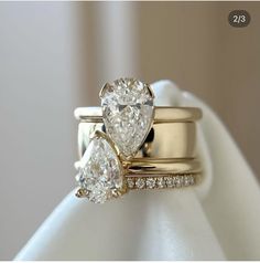 two pear shaped diamond engagement rings on top of each other, with the wedding band set in yellow gold