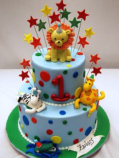 a three tiered birthday cake decorated with animals, stars and numbers on the top