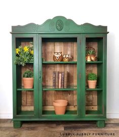 a green bookcase with potted plants on top