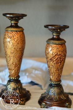 two gold colored vases sitting on top of a bed next to eachother