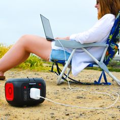 a woman sitting in a lawn chair with a laptop on her lap, next to a portable radio