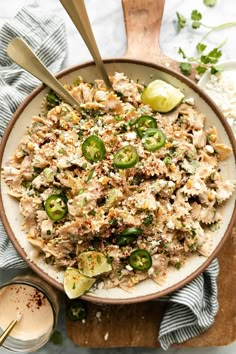 a white bowl filled with chicken and vegetables next to a wooden spoon on top of a cutting board