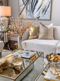 a living room filled with lots of furniture and gold accessories on top of tables in front of a painting