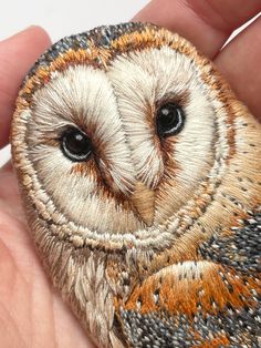 an embroidered owl is shown in the palm of someone's hand and it appears to be holding something