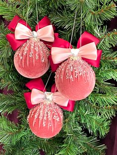 three ornaments hanging from a christmas tree with red ribbons and bows on it's sides