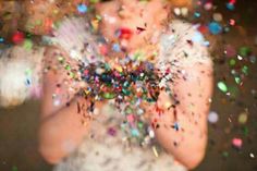 a woman is covered in confetti and sparkles while holding her hands together