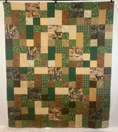 a green and brown quilt hanging on a wall