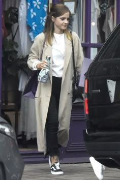 a woman walking down the street in front of a car