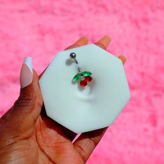 a hand holding a piece of white glass with a red berry on it and green leaves