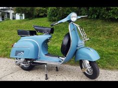 a blue scooter parked on the side of a road next to some grass