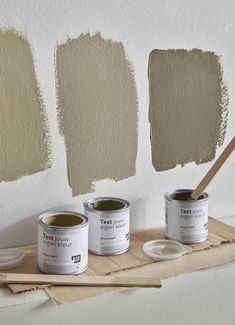 three cans of paint sitting on top of a wooden tray