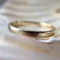 a close up view of a gold wedding ring on a white marble slabd surface