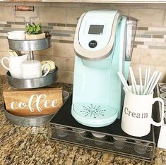 a coffee maker sitting on top of a counter next to cups and utensils